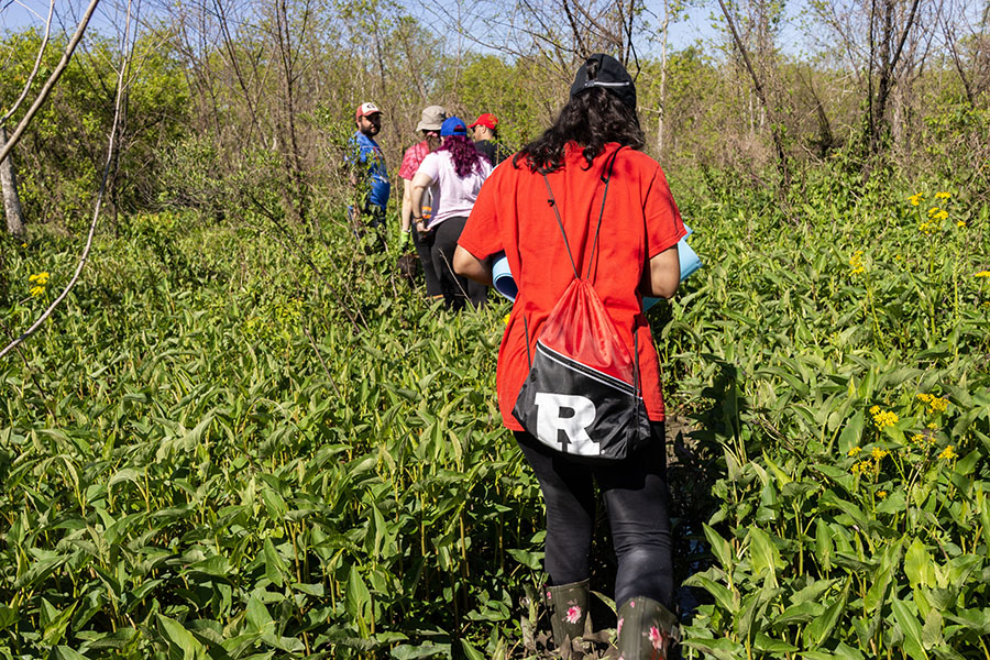 Students trudge through mud to find a suitable location to plant cypress trees at Bayou Savauge